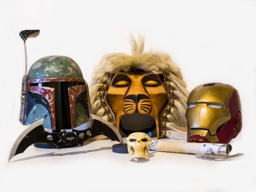 Colección de cascos y props: Boba Fett, Rey León, Iron Man, sable de luz y batarang.